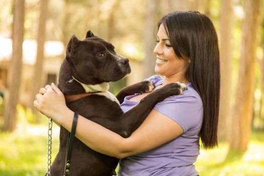 Beautiful young woman with her cute stafford terrier hugging in the park.