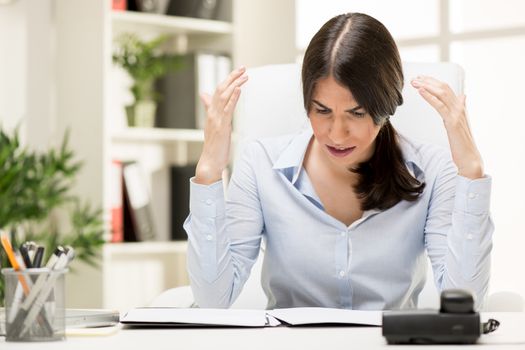 Portrait of a Frustration young businesswoman sitting in the office looking on the document.