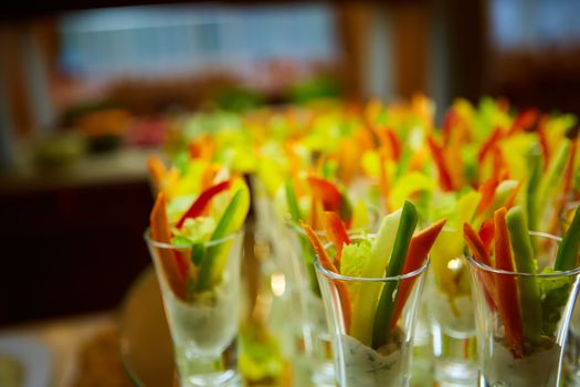 Colorful slices of raw vegetables in glasses carrots, celery, cucumber, sweet pepper and yogurt sauce. The concept of diet, healthy and vegetarian food. Selective focus