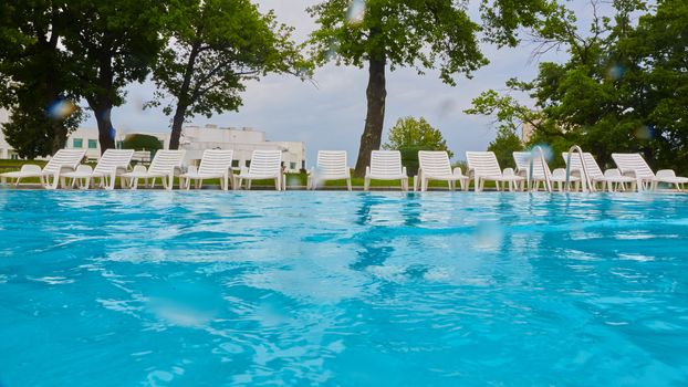 wimming pool with blue water and empty sunbed.