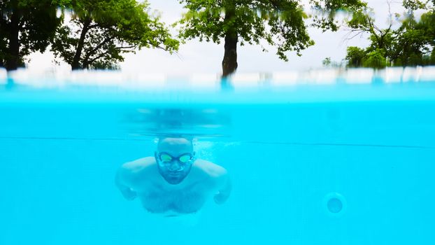 Male Swimmer Under Water in hotel Pool.