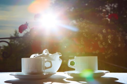 white teapot, two cups and sun. Garden party