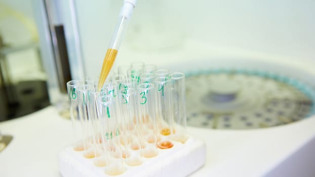 A pipette dropping sample into a test tube,abstract science background. Shallow dof