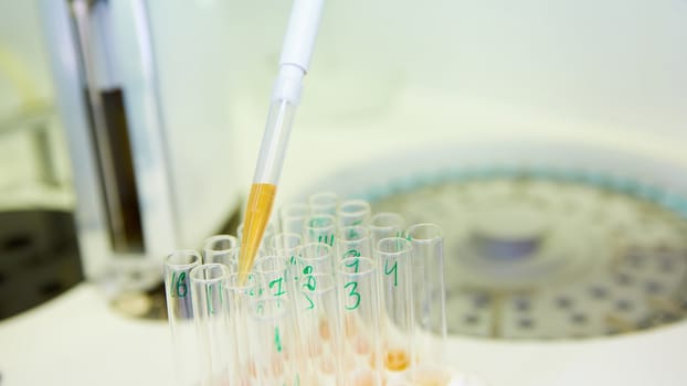A pipette dropping sample into a test tube,abstract science background. Shallow dof