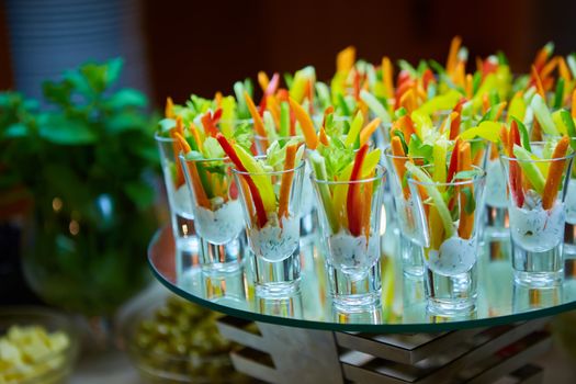 Colorful slices of raw vegetables in glasses carrots, celery, cucumber, sweet pepper and yogurt sauce. The concept of diet, healthy and vegetarian food. Selective focus
