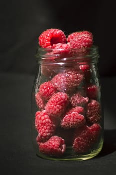 fresh raspberries in glass on black background