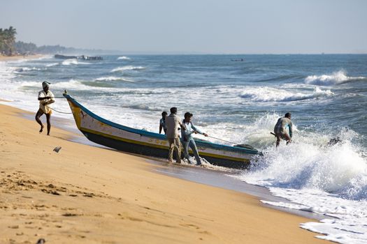 Pondichery, Tamil Nadu, India - February 27, 2014 : Traditional fishermen on beach, on sea, on sand. Long boats, Hard work poor people