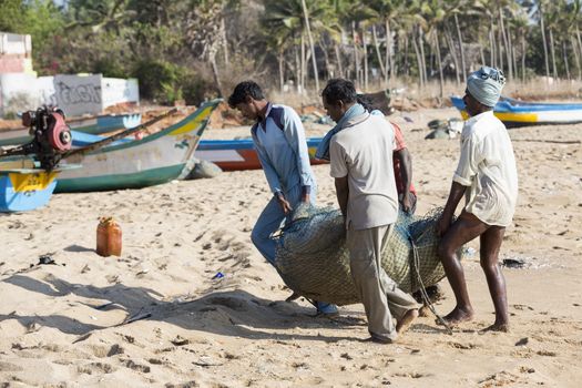 Pondichery, Tamil Nadu, India - February 27, 2014 : Traditional fishermen on beach, on sea, on sand. Long boats, Hard work poor people