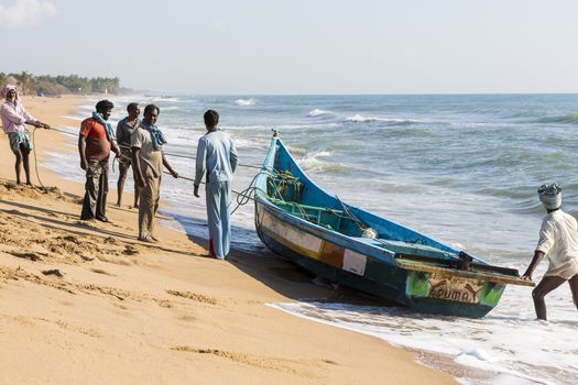 Pondichery, Tamil Nadu, India - February 27, 2014 : Traditional fishermen on beach, on sea, on sand. Long boats, Hard work poor people