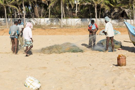 Pondichery, Tamil Nadu, India - February 27, 2014 : Traditional fishermen on beach, on sea, on sand. Long boats, Hard work poor people