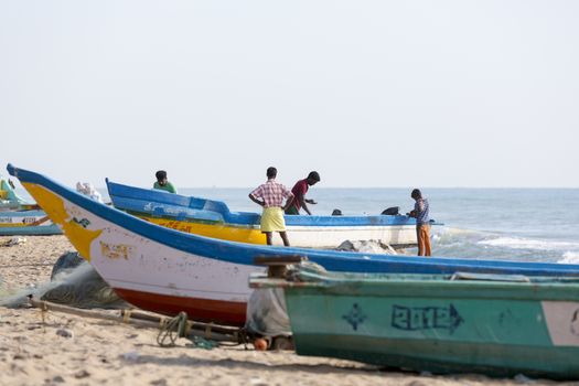 Pondichery, Tamil Nadu, India - February 27, 2014 : Traditional fishermen on beach, on sea, on sand. Long boats, Hard work poor people