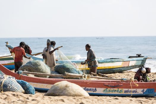 Pondichery, Tamil Nadu, India - February 27, 2014 : Traditional fishermen on beach, on sea, on sand. Long boats, Hard work poor people