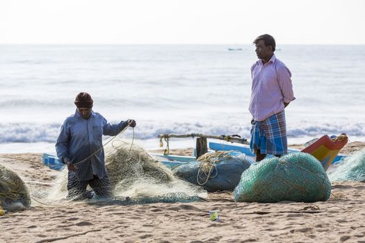 Pondichery, Tamil Nadu, India - February 27, 2014 : Traditional fishermen on beach, on sea, on sand. Long boats, Hard work poor people