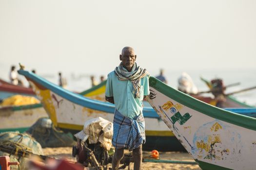 Pondichery, Tamil Nadu, India - February 27, 2014 : Traditional fishermen on beach, on sea, on sand. Long boats, Hard work poor people