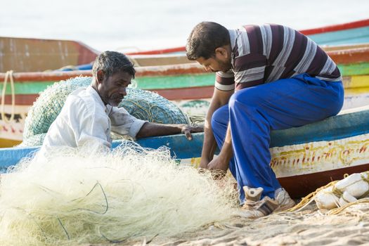 Pondichery, Tamil Nadu, India - February 27, 2014 : Traditional fishermen on beach, on sea, on sand. Long boats, Hard work poor people