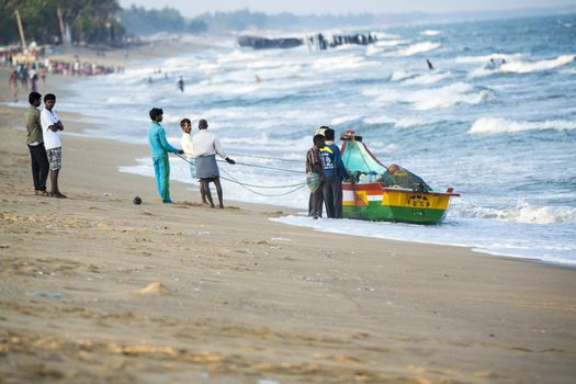 Pondichery, Tamil Nadu, India - February 27, 2014 : Traditional fishermen on beach, on sea, on sand. Long boats, Hard work poor people