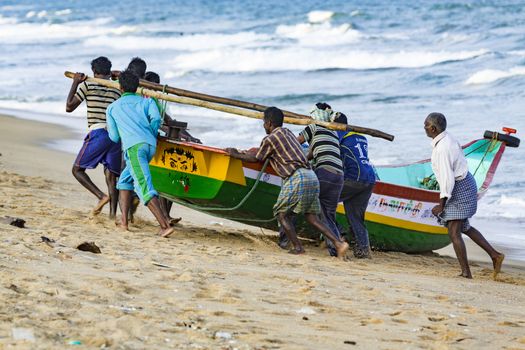 Pondichery, Tamil Nadu, India - February 27, 2014 : Traditional fishermen on beach, on sea, on sand. Long boats, Hard work poor people