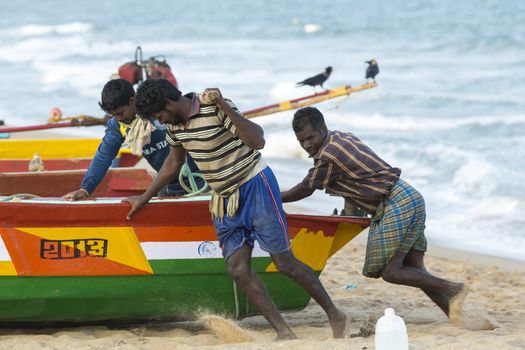 Pondichery, Tamil Nadu, India - February 27, 2014 : Traditional fishermen on beach, on sea, on sand. Long boats, Hard work poor people