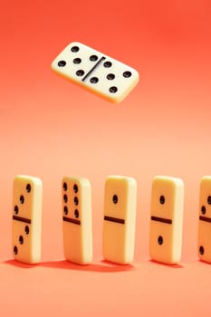 White dominoes standing in a row on red background. One domino above