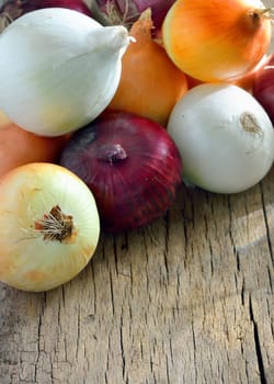 Different types of onion on wooden table