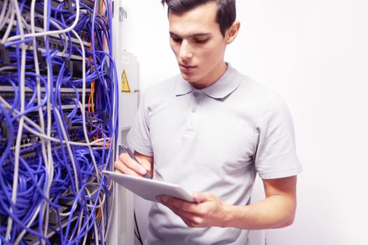 Young engeneer man in network server room with digital tablet