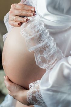 Pregnant Woman holding her hands on her stomach belly at home