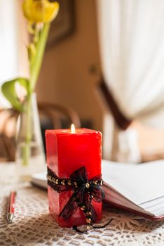 red candle burns on a background of an open book with a red pen