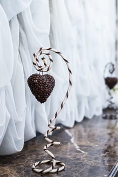 Heart of coffee beans hanging on a striped holder