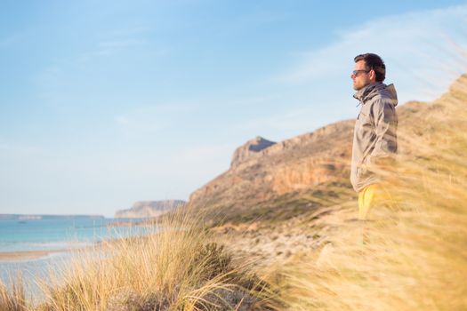 Sporty active man looking at distance, enjoying beautiful nature, freedom and life at serene landscape at Balos beach. Active lifestyle outdoors.
