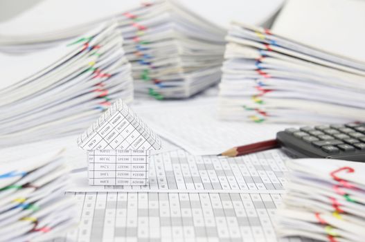 House on finance account have blur brown pencil with calculator and pile overload paperwork of report and receipt with colorful paperclip place as background.