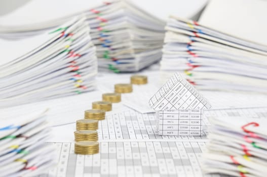 House on finance account have blur pile line of gold coins and pile overload paperwork of report and receipt with colorful paperclip place as background.