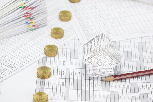 House with brown pencil and pile line of gold coins on finance account have blur pile overload paperwork of report and receipt with colorful paperclip place as background.