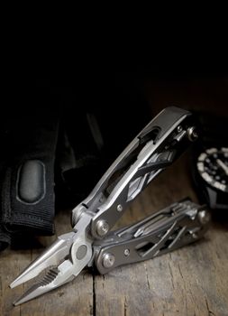 stainless steel multitool isolated on wooden table