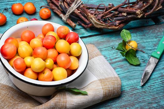 Iron bowl with autumn plums on wooden background