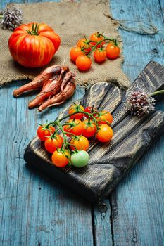 Ripe tomatoes of two varieties on the kitchen table in rustic style
