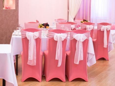 Close-up of white wedding chairs in pink color