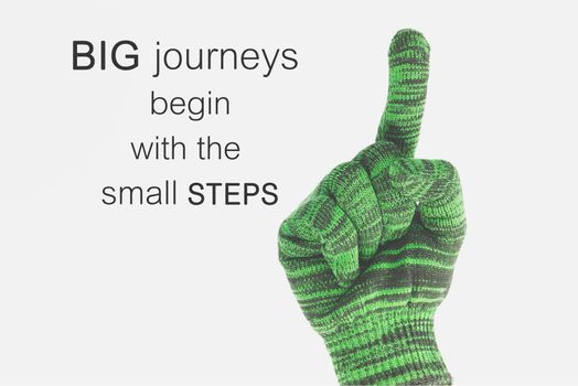 Word  Big journeys begin with the small steps.Inspirational motivational quote on Green woven gloves appearance of leadership background