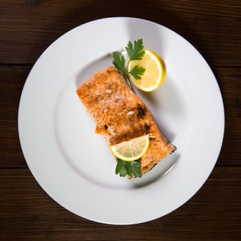 High Angle View Of Grilled Salmon In Plate with lemon and parsley