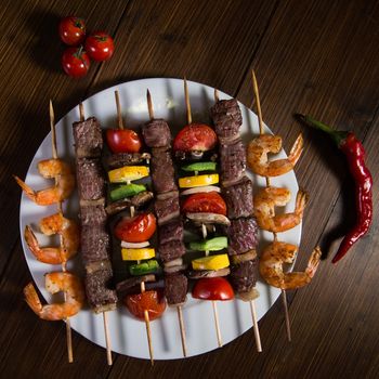 Skewered meat, shrimp and vegetables on a plate, Studio shoot