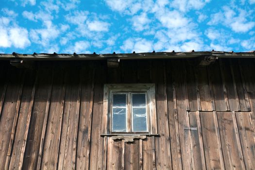 A window in a wooden wall with sky background
