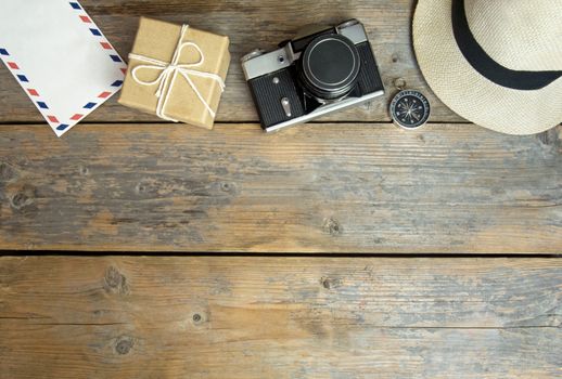 Camera, international envelope, hat and compass over a wooden  background with space