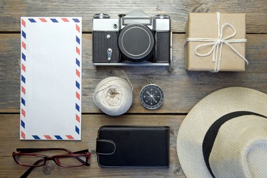 Camera, envelope, hat and compass over a wooden  background