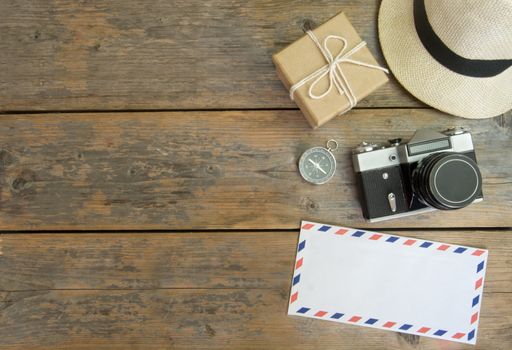 Camera, international envelope, hat and compass over a wooden  background with space 