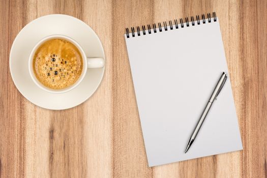 Coffee cup, spiral notebook and pen on the wooden table