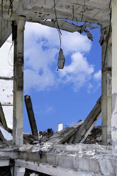 Blue sky in the opening wall of the destroyed building and concrete debris.