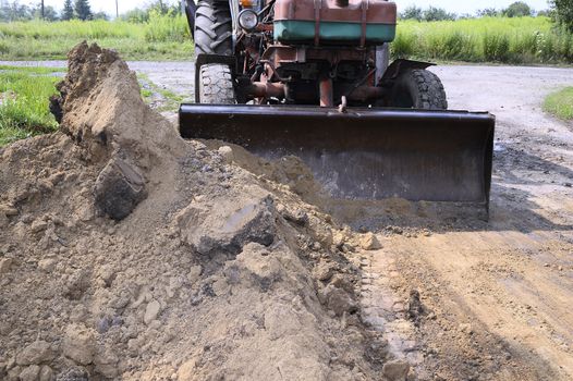 Excavator bucket digging a trench in the dirt ground.