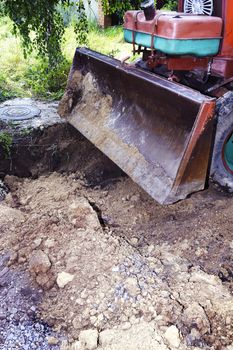 Excavator bucket digging a trench in the dirt ground.