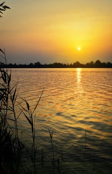 Landscape with sunset over the lake with the reflection of light on the surface of the water