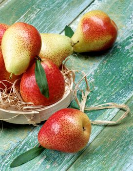 Heap of Ripe Yellow and Red Pears with Leafs in Wicker Bowl Cross Section on Cracked Wooden background