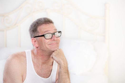 Handsome retro style man with glasses on a white bed